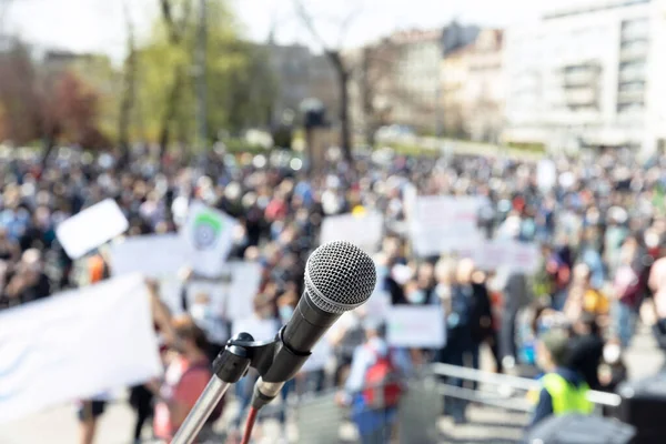 Protesto ya da halk gösterileri, mikrofona odaklanmak, arka planda bulanık bir grup insan