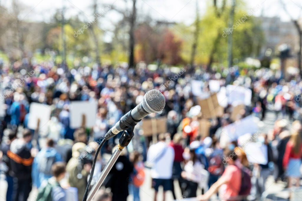 Protest or public demonstration, focus on microphone, blurred crowd of people in the background