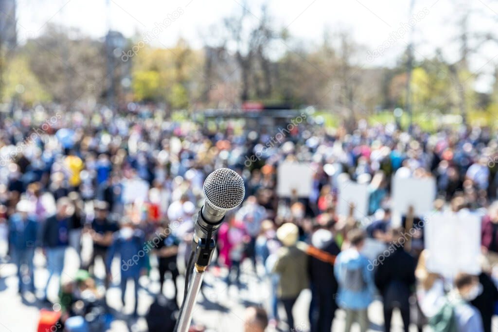 Protest or public demonstration, focus on microphone, blurred crowd of people in the background