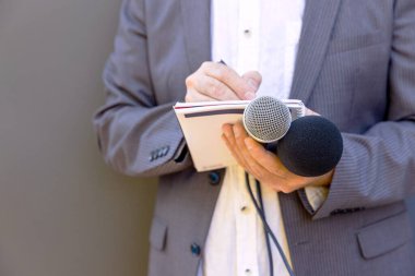 Medya etkinliğinde ya da basın konferansında, mikrofonu elinde tutan, notlar yazan bir gazeteci. Yayın gazeteciliği kavramı.