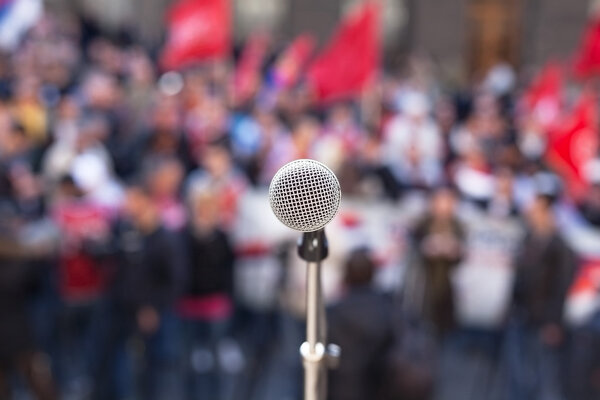 Microphone in focus against unrecognizable crowd of people