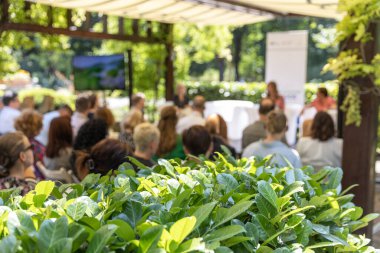 Profesyonel seyircilerle açık hava iş konferansı yeşil bahçe mekanında sunuma katılıyor, tepe örtüsü altında, sürdürülebilir şirket etkinliği ayarları