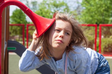 Oyun bahçesindeki ses kanallarını dinleyen meraklı genç kız, açık hava oyun ekipmanlarını, çocukluk merakını, hayal gücünü, öğrenmeyi ve parlak bir park ortamında duyusal oyunu keşfediyor.