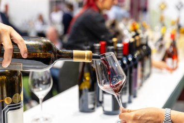 Şarap tadımı etkinliği şarap ve içecek sergisinde konuklar için kırmızı şarap dolduran şarap garsonuyla