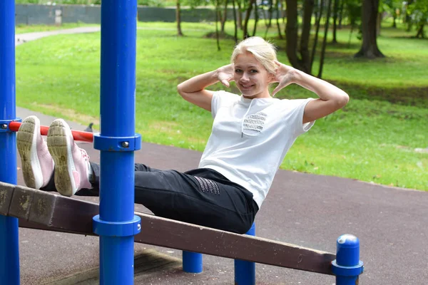 Frauenturnen. Mädchen schüttelt im Freien die Bauchpresse. — Stockfoto