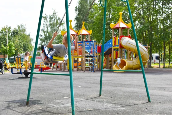 Dzieci bawią się na placu zabaw w parku miejskim w lecie. — Zdjęcie stockowe