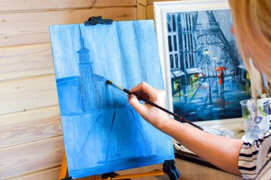 Kız ressam evde tuvale yağlı boyalarla resim çiziyor..