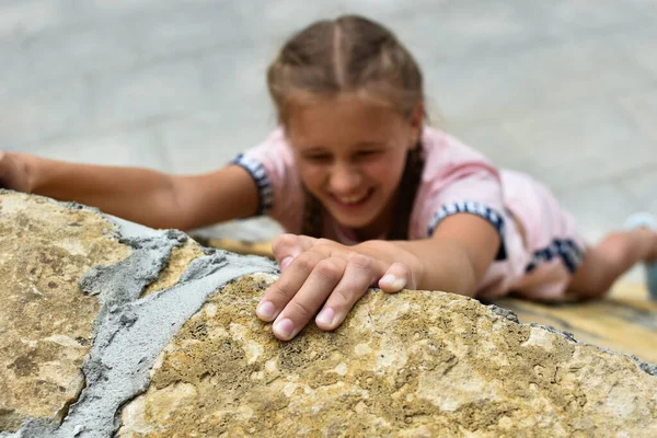 Девочка поднимается на высокую каменную гору в природе — стоковое фото