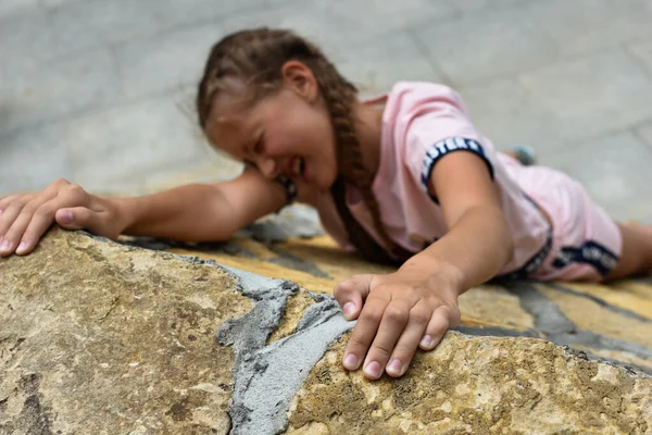 Девочка поднимается на высокую каменную гору в природе — стоковое фото
