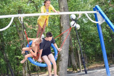 Komik çocuklar büyük bir salıncakta sallanıyor, oyun alanında gülen çocuklar.,