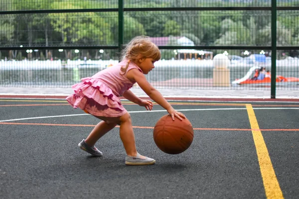 Hermosa niña caucásica con una gran bola en el campo de juego. — Foto de Stock