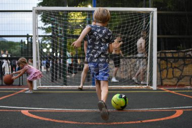 Koçu olan bir çocuk sahada futbol oynuyor. Bir adam küçük bir futbolcuyu eğitir..