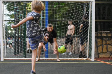 Koçu olan bir çocuk sahada futbol oynuyor. Bir adam küçük bir futbolcuyu eğitir..