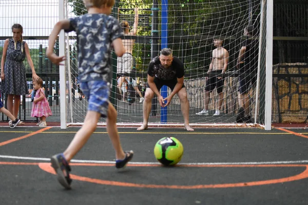 コーチのいる少年は野球場でサッカーをする。ある男が小さなサッカー選手を訓練し. — ストック写真