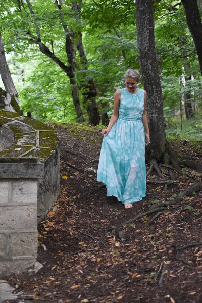 Yeşil orman parkında uzun açık yeşil elbiseli zarif bir kız..