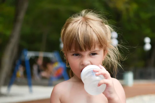 Holčička pije drink z bradavky venku. batole dívka s lahví vody — Stock fotografie