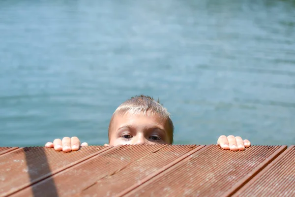 boy child swims in city water lake, bathing season is open.