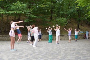 Açık hava parkında fiziksel egzersiz yapan bir grup kadın. Halka açık bir yerde meditasyon.