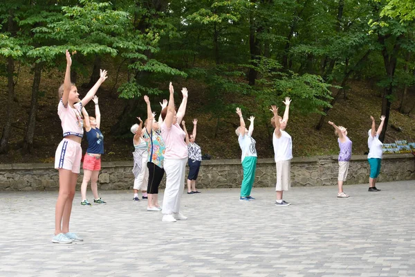 Groep vrouwen doet fysieke oefeningen in het openlucht park. helende meditatie op een openbare plaats. — Stockfoto