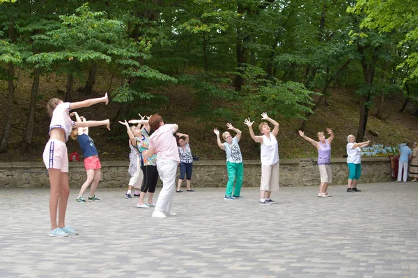 Groep vrouwen doet fysieke oefeningen in het openlucht park. helende meditatie op een openbare plaats. — Stockfoto