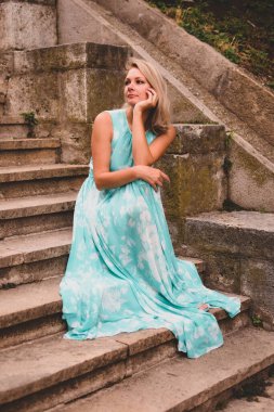 Genç sarışın kadın sakince doğada dinleniyor, düşünüyor ve içeri girmek istiyor..