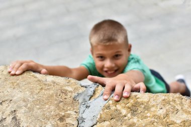 Bir çocuk teçhizatsız taştan bir dağa tırmanıyor, tehlikeli bir tırmanış..