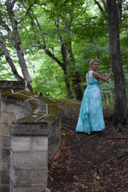 Ormanda tek başına yürüyen güzel bir kadın, uzun açık renk elbiseli bir kadın...