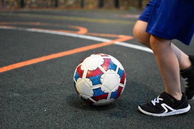 Oğlan babasıyla futbol oynuyor. Genç futbolcu spor alanında antrenman yapıyor.