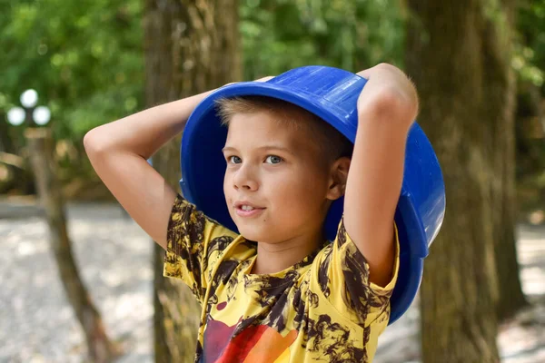 Мальчик с тазом на голове. the child put a task on his head. — стоковое фото