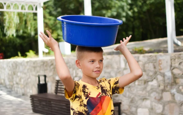 Мальчик с тазом на голове. the child put a task on his head. — стоковое фото