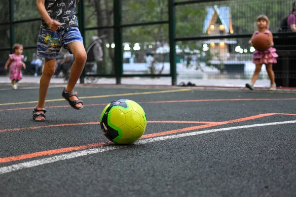 Oğlan babasıyla futbol oynuyor. Genç futbolcu spor alanında antrenman yapıyor.