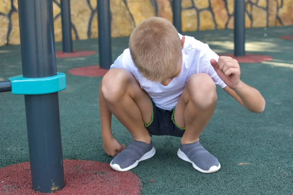 Niño se sienta en el patio al aire libre. retrato de un atleta varón rubio — Foto de Stock