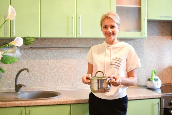 Улыбающаяся домохозяйка с кастрюлей супа на кухне. — стоковое фото