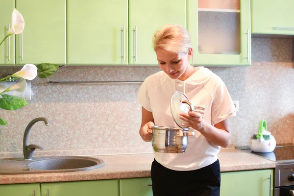 Femme au foyer souriante avec une casserole de soupe dans la cuisine. — Photo