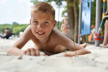Çocuk kumsalda kumlarda oynuyor, çocuk sıcak kumun altında saklanıyor.,