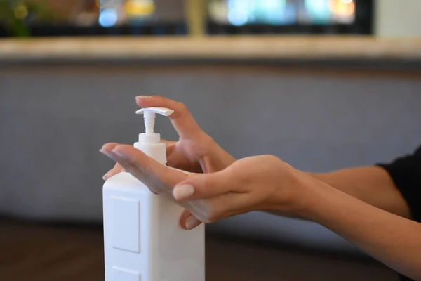 beautiful young woman disinfects hands, person cleans hands with sanitary solution.