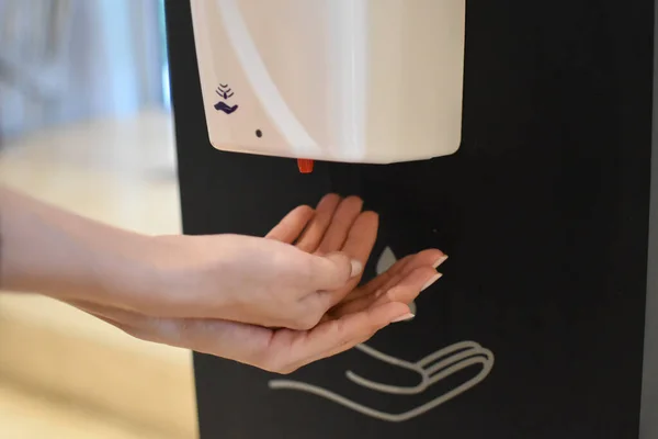 beautiful young woman disinfects hands, person cleans hands with sanitary solution.