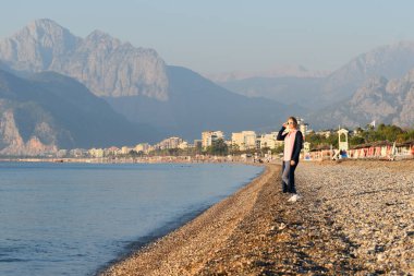Kadın kayalık sahil boyunca yürüyor. Uçmak için kenarlıkları aç.