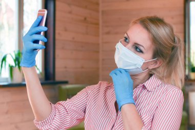 Tıbbi koruyucu maskeli bir kadın telefonda konuşuyor..