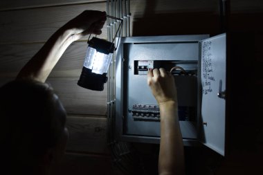 Power outage in house. Extra light went out in room. A person with a lantern checks electrical panel. clipart