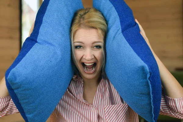 Retrato de mujer cansada enojada en casa. mujer cubrió sus oídos con almohadas. —  Fotos de Stock