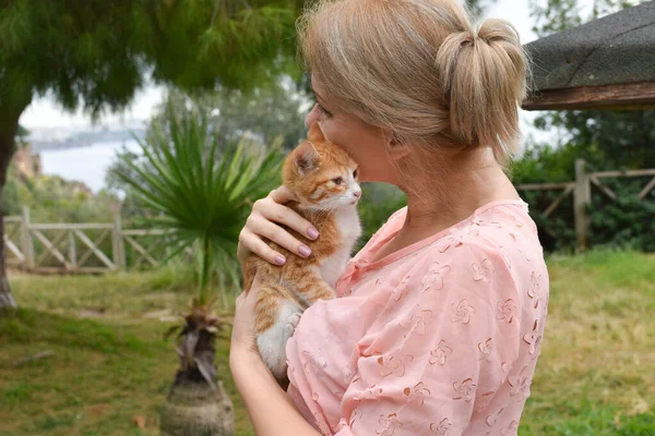 Una mujer con un gatito pequeño al aire libre. Cuidar y proteger a los gatos callejeros. —  Fotos de Stock