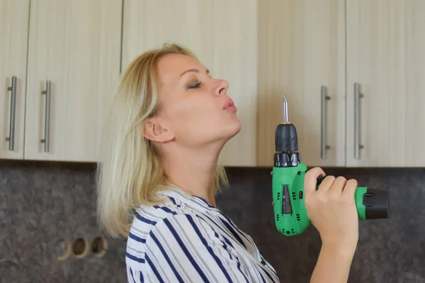 Una joven con un taladro en la mano. chica ama de casa hace reparaciones en el apartamento. — Foto de Stock