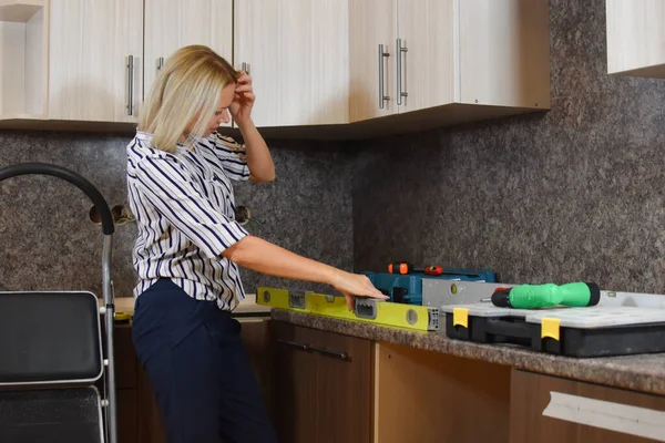 La mujer triste hace reparaciones. Mala chica constructora en casa repara la cocina. — Foto de Stock