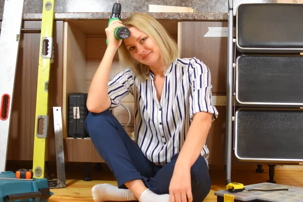 La mujer triste hace reparaciones. Mala chica constructora en casa repara la cocina. — Foto de Stock