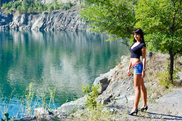 Hermosa chica de pie en la orilla de un río de montaña —  Fotos de Stock