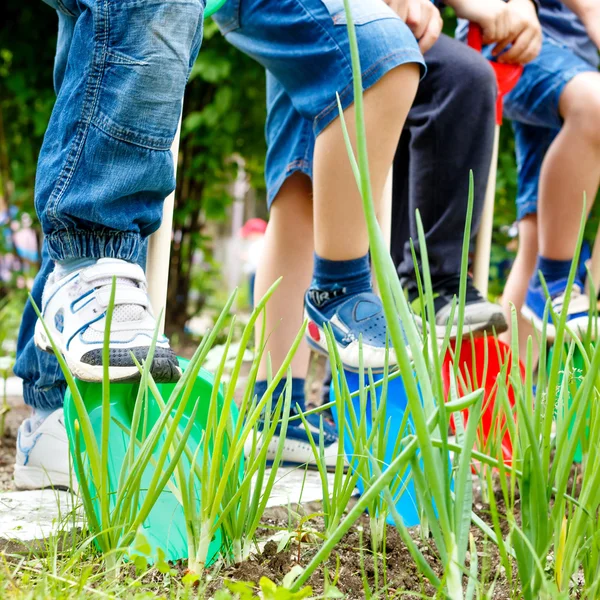 Eine Gruppe von Kindern spielt mit Plastikschaufeln im Garten — Stockfoto