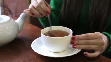 Kadın beyaz bir fincan çay karıştırma. Yakın çekim