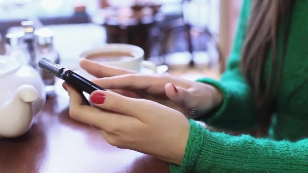 Mujer está utilizando el teléfono inteligente en un café, navegar por las fotos en una red social . — Vídeos de Stock