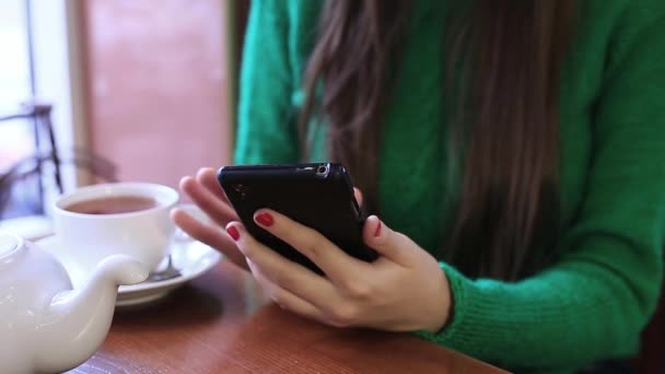 Mujer está utilizando el teléfono inteligente en un café, navegar por las fotos en una red social . — Vídeo de stock